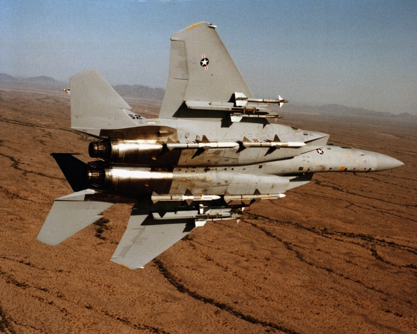 An air-to-air underside view of an F-15 Eagle aircraft from the 555th Tactical Fighter Training Squadron, 405th Tactical Training Wing, Luke Air Force Base, Arizona, banking to the left. The aircraft is equipped with four AIM-9 Sidewinder missiles on the wing pylons and four fuselage-mounted AIM-7 Sparrow missiles.